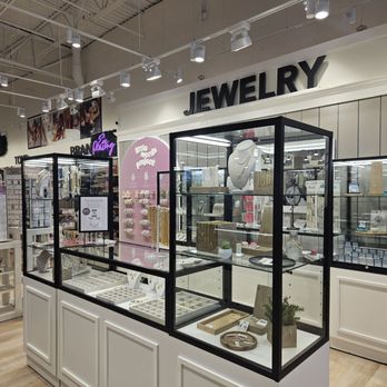 Uncharted - A jewelry display case in a retail store showcases necklaces, rings, and accessories, with a large 'JEWELRY' sign above. - Accessories Near Me - Oak Brook, Illinois