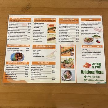Wrap N Roll - Back of menu - Menu from a Vietnamese restaurant displaying various food categories including rice plates, sandwiches, noodle bowls, and kid's meals. Items include grilled pork, chicken, shrimp, Vietnamese ham, and vegetarian options, with prices ranging from approximately $5 to $17. The menu also features salad bowls, crunchy rice clay pots, and noodle soups such as lemongrass beef and chicken/tofu. The menu is printed on a single sheet with images of some dishes and the restaurant's contact information. - Vietnamese Near Me - Albuquerque, New Mexico