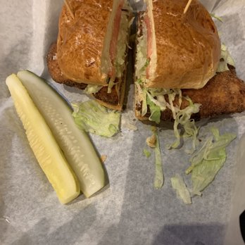 The Patio - Crispy chicken - A fried fish sandwich with lettuce and tomato inside a toasted bun, served with two pickle spears on the side. - Barbeque Near Me - Lombard, Illinois