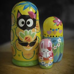 Classic Waves Boutique - Adorable island-inspired Matryoshka dolls featuring a cat, parakeet & rabbit, with colorful tropical details and sunny yellow accents.