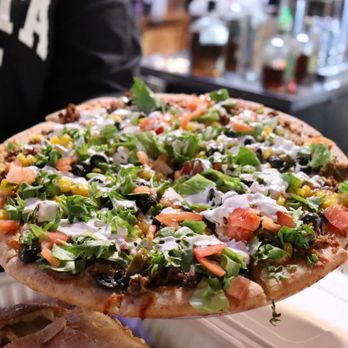 Muddy's Tavern - a person holding a pizza - Sports Bars Near Me - Watervliet, New York Muddy's Tavern - a person holding a pizza - Sports Bars Near Me - Watervliet, New York