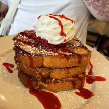 Tank and Libby's - Crme Brulee French Toast - Three slices of French toast topped with whipped cream and red syrup, served on a plate with powdered sugar. - Breakfast & Brunch Near Me - Drexel Hill, Pennsylvania