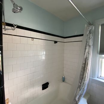 Sanchez Cleaning Service - Made the original work come back to life - A bathroom shower area with white subway tiles, a shower curtain, and a window with blinds, featuring a bathtub and a showerhead. - Home Cleaning Near Me