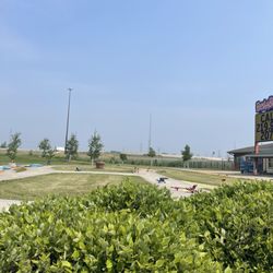 Bellaboo’s children's Play & Discovery Center - Outside area. There is a race track with trikes, and beyond there in the distance there is a pirate themed playground and splash pad areas.