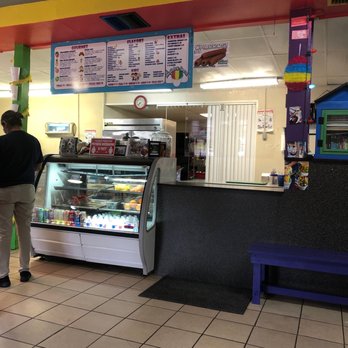 Rainbow Snow Cones - a man standing in front of a counter - Desserts Near Me - Dallas, Texas