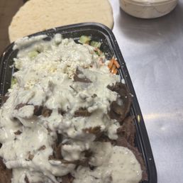 Beef and lamb rice bowl with white sauce, and a side of hummus. Beef and lamb rice bowl with white sauce, and a side of hummus.