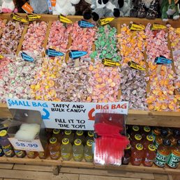 So much taffy and so many flavors - Colorful taffy candies are arranged in separate sections with flavor labels, alongside bottled sodas below, in a candy store.