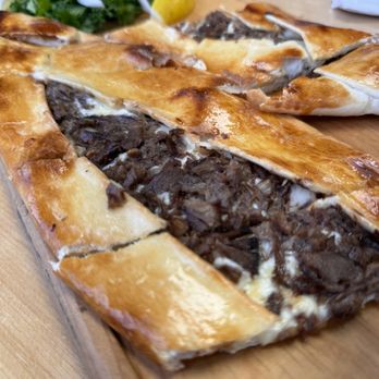 Pizza-Pide - a piece of meat and vegetables on a cutting board - Pizza Near Me - Toronto, Ontario Pizza-Pide - a piece of meat and vegetables on a cutting board - Pizza Near Me - Toronto, Ontario