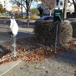 Poop bag station and a bag of toys hanging on the fence.