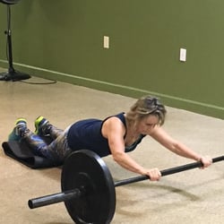 Trainer Linda Bock performing a 90lb barbell roll out.