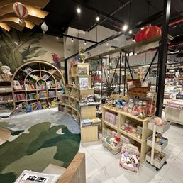 Interior of a bookstore with bookshelves, display tables with toys, and decorative elements like lanterns and wall art.