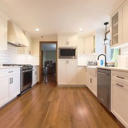 Stately Builders - Spacious kitchen with ample natural light, featuring hardwood floors and white cabinets.