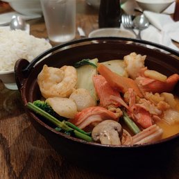 Red Curry Seafood - A bowl of seafood curry with shrimp, vegetables, and sauce, accompanied by a bowl of white rice on a wooden table.