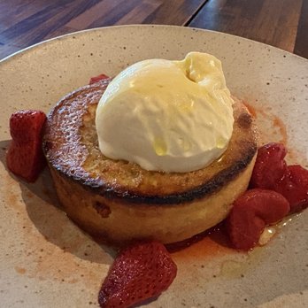 Prairie Fire - Olive oil cake with wood fired strawberries - A dessert plate with a grilled bread slice topped with ice cream, garnished with strawberries on a speckled ceramic plate. - Pizza Near Me - Brookline, Massachusetts