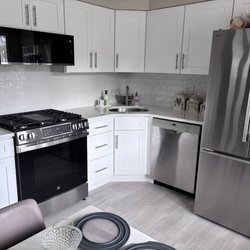 Fina Cabinets LLC - After kitchen. New wood cabinets, backsplash. Quartz countertop. New floor. New steel sink. Microwave raised over oven.