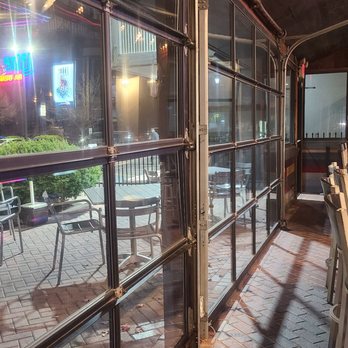 Craft'd - Outdoor seating wraps the building - Interior view of a restaurant with a bar counter and chairs, adjacent to large glass windows showing outdoor patio seating. - American Near Me - Plainfield, Illinois