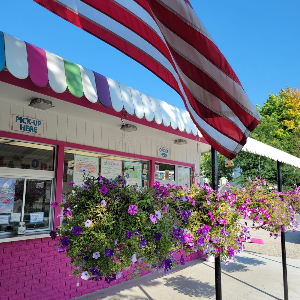 A La Mode - Front of A La Mode. Pink bldg with pink and purple flowers underneath an American flag. - Ice Cream & Frozen Yogurt Near Me - Spring Lake, Michigan