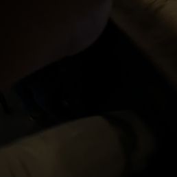 My horrible picture of my wings lol - sorry - A low-light, blurry image appears to be taken inside a vehicle, showing a seat and a person's leg, with limited visible details.