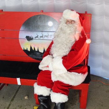 Target - A grateful elf to an employee who was right on Target. - Santa Claus, dressed in a traditional red suit with white fur trim, is seated on a red bench in front of a holiday-themed background featuring a silhouette of Santa's sleigh and reindeer. - Department Stores Near Me - Brighton, Michigan