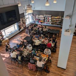 Cardboard Classic Games - Groups of people are sitting at tables playing trading card games