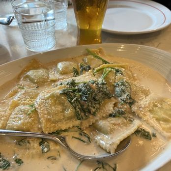 Mia Francesca  - Ravioli Ai Spinaci - A dish of ravioli ai spinaci served with a creamy sauce, garnished with spinach and cheese, on a restaurant table with a glass of beer. - Italian Near Me - Chicago, Illinois