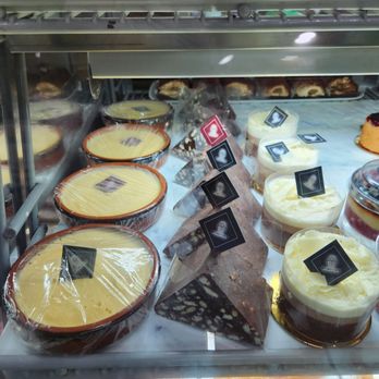 Belmo Cafe - More choices. - A glass display case contains an assortment of cakes and desserts, including cheesecakes, chocolate slices, and mousse cups, with small labels indicating flavors. - Coffee & Tea Near Me - Berkeley, California