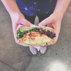 Neopol Savory Smokery - Smoked salmon sandwich with avocado, tomatoes, and lettuce on sunflower flaxseed bread