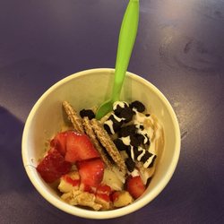 Cheesecake and salted caramel froyo with cheesecake cubes, strawberries, wafers, brownie bits and a drizzle of sauce.