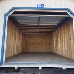 A Plus Storage - Empty enclosed storage unit with an open roll-up door and wood-lined interior.