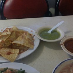 Plate of complimentary chips drizzled with queso and 2 sauces.