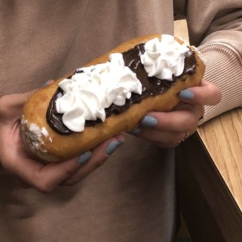 Deluxe Donuts - a woman holding a chocolate covered donut - Donuts Near Me - Anderson, Indiana Deluxe Donuts - a woman holding a chocolate covered donut - Donuts Near Me - Anderson, Indiana