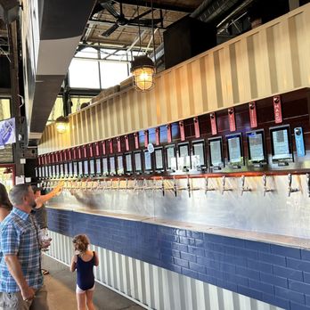 Stanley Beer Hall - a man and a little girl standing in front of a row of beer taps - Beer Gardens Near Me - Aurora, Colorado Stanley Beer Hall - a man and a little girl standing in front of a row of beer taps - Beer Gardens Near Me - Aurora, Colorado