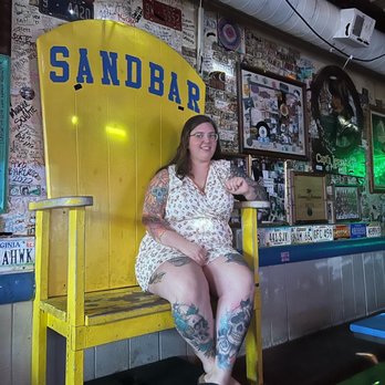 The Sandbar - a woman sitting on a yellow bench - Bars Near Me - Lawrence, Kansas The Sandbar - a woman sitting on a yellow bench - Bars Near Me - Lawrence, Kansas