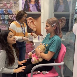 Piercing station. My daughter, her bestie, and our hero of the day.
