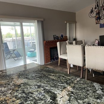 Harold White Tile Work - Fireplace before - Interior living space featuring a brick fireplace, dining chairs, and a sliding glass door to an outdoor patio with lounge chairs. - General Contractors Near Me - Riverside, California