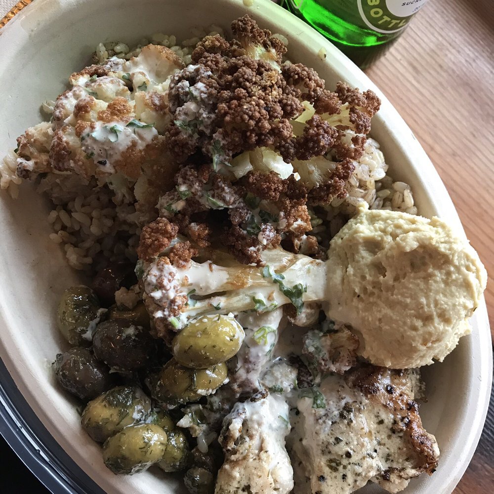 Half chicken, half cauliflower brown rice bowl with olives, hummus and tahini sauce. Half chicken, half cauliflower brown rice bowl with olives, hummus and tahini sauce.