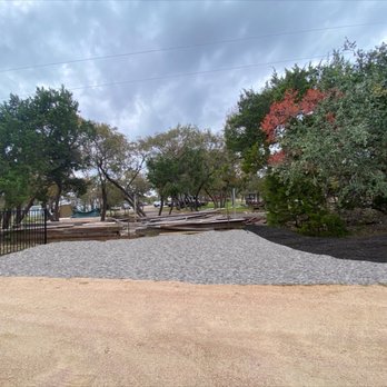 Villa’s Landscape - a graveled area with trees and a playground in the background - Lawn Services Near Me Villa’s Landscape - a graveled area with trees and a playground in the background - Lawn Services Near Me