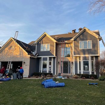 Fiji Construction - Those are some tall ladders!!!  Project Manager was constantly there checking on things!!! - Construction workers are repairing the roof of a two-story house with ladders and safety harnesses in daylight. - Roofing Near Me - Cary, Illinois