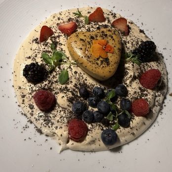 Platea - A dessert featuring a heart-shaped cake on a white plate, garnished with fresh strawberries, blueberries, blackberries, microgreens, and edible flower petals, with a creamy base. - Peruvian Near Me - Pinecrest, Florida