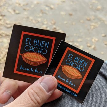 El Buen Cacao - a person holding two stickers - Chocolatiers & Shops Near Me - Idyllwild, California El Buen Cacao - a person holding two stickers - Chocolatiers & Shops Near Me - Idyllwild, California