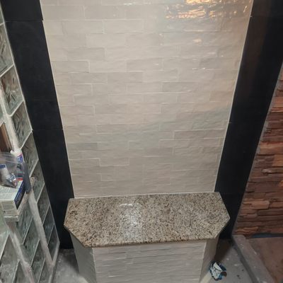 Bathroom remodel 2023 - Bathroom remodel featuring a half moon glass block and tile European style walk in shower, a custom hand crafted glass pebble shower floor, stacked stone throughout, custom dimmable lighting, a black bathroom vanity, vessel sink, toilet and towel bar install. Bathroom remodel 2023 - Bathroom remodel featuring a half moon glass block and tile European style walk in shower, a custom hand crafted glass pebble shower floor, stacked stone throughout, custom dimmable lighting, a black bathroom vanity, vessel sink, toilet and towel bar install.