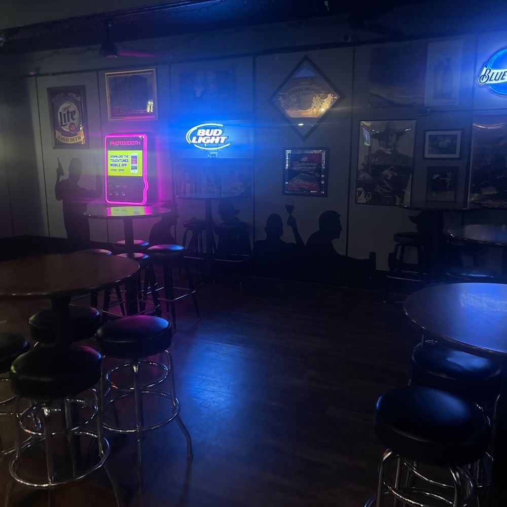 a bar with stools and neon signs a bar with stools and neon signs