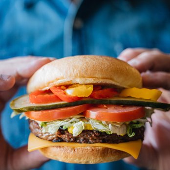 Harvey's - a person holding a hamburger - Burgers Near Me - Vimont, Quebec