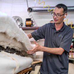 An Oklahoma Mattress Company craftsman adds another layer of cotton to an innerspring mattress.