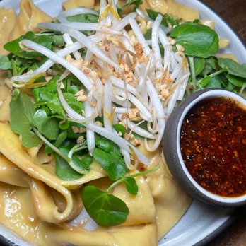 Cloud & Spirits - Xi'an street noodle - Plate of dumplings garnished with bean sprouts, fresh greens, and crushed peanuts, accompanied by a spicy dipping sauce. - New American Near Me - Cambridge, Massachusetts