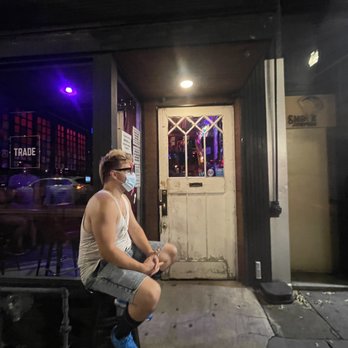 Trade - a man sitting on a stool in front of a store - Gay Bars Near Me - Washington, DC, District of Columbia
