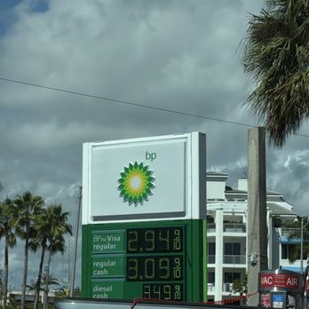 bp - "$2.94" - A BP gas station sign shows fuel prices for regular, cash, and diesel, with a background of palm trees and a cloudy sky. - Gas Stations Near Me - JUPITER, Florida