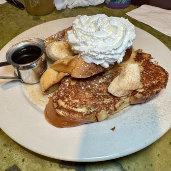 Bella's Cafe - "Challah French Toast" (with bananas) - French toast with whipped cream, banana slices, and syrup served on a white plate, with apple slices and powdered sugar. - Breakfast & Brunch Near Me - New Haven, Connecticut