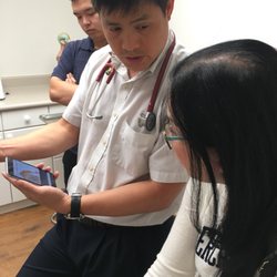 VM Clinic - He is showing anatomy pictures while analyzing her numbing hands for her to fully understand the problem
