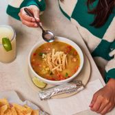 TORTILLA SOUP Homemade chicken broth w/roasted chicken, corn, green chiles, tomatoes & cilantro, topped w/cheese, avocado & tortilla strips.